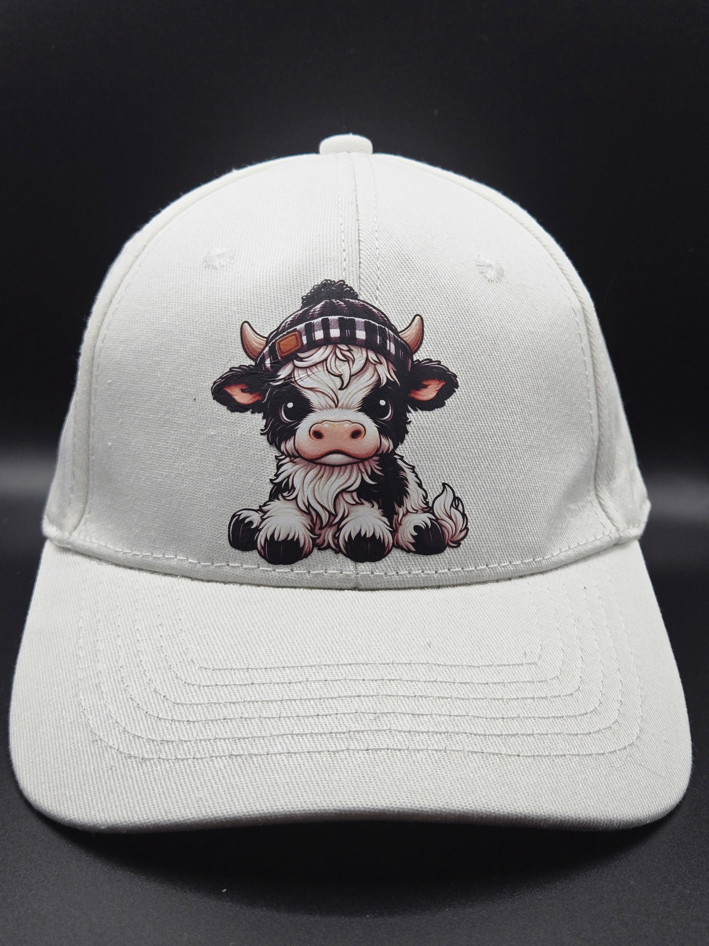 White hat with black and white highland cow